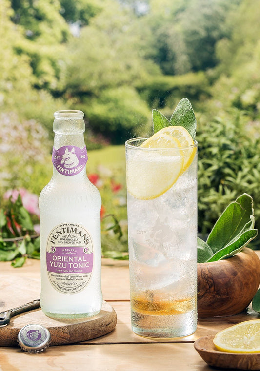 Botanist Buzz cocktail in a garden setting beside a bottle of Fentimans Oriental Yuzu Tonic