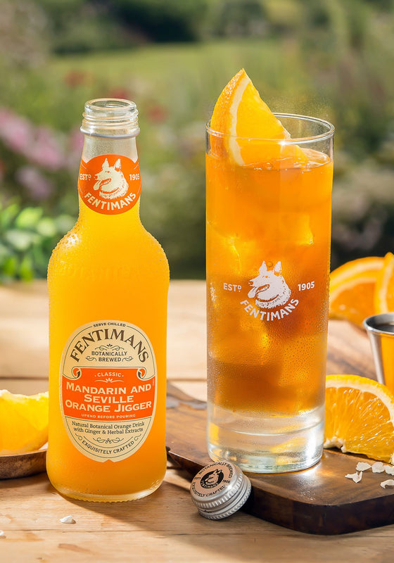 A bottle of Fentimans Mandarin & Seville Orange Jigger beside a highball serve garnished with orange